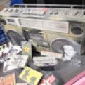 Boobmbox e cassette di Simonon del 1982. A sinistra una foto della band scattata da Patti Smith, colorata a mano da Simonon